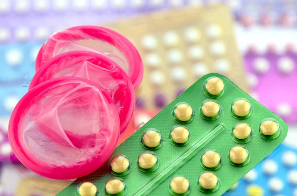 Condom and oral contraceptive pill on pharmacy counter.