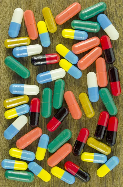 Colorful Oral Medication in Hard Gelatin Capsules on Vintage Wood Background.