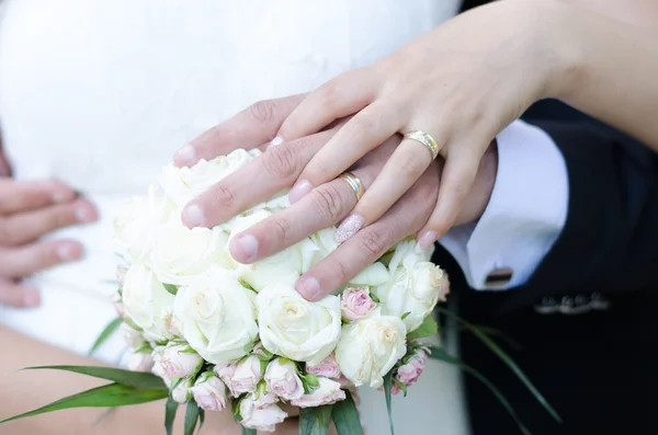 Bride and groom with their hands on the bride\'s bouquet