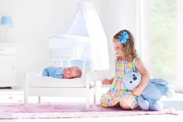 Little girl playing with newborn baby brother