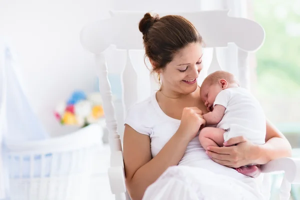 Mother and newborn baby in white nursery