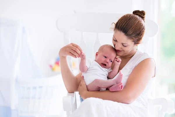 Mother and newborn baby in white nursery