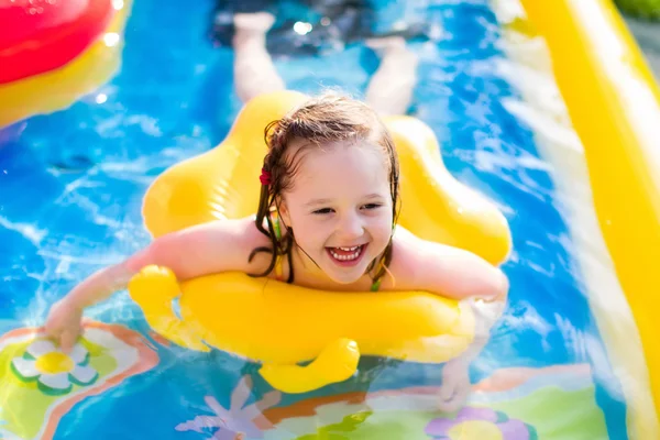 Little girl playing in inflatable garden swimming pool