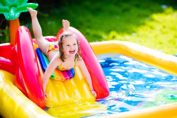 Little girl playing in inflatable garden swimming pool