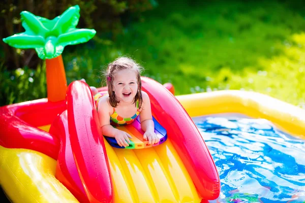 Little girl playing in inflatable garden swimming pool