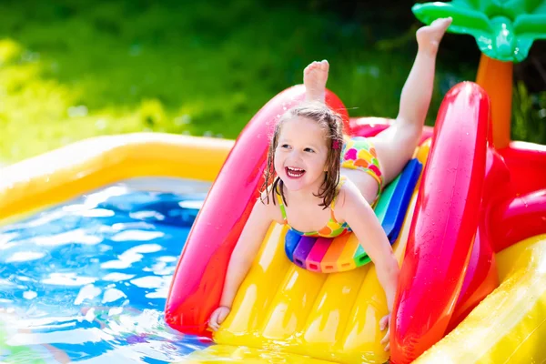 Little girl playing in inflatable garden swimming pool