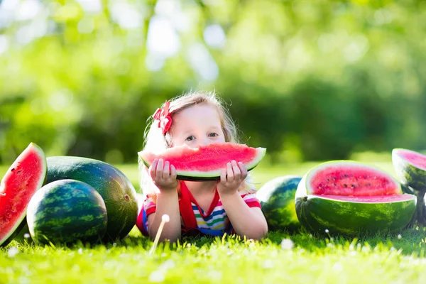 Little girl eating watermelon in the garden