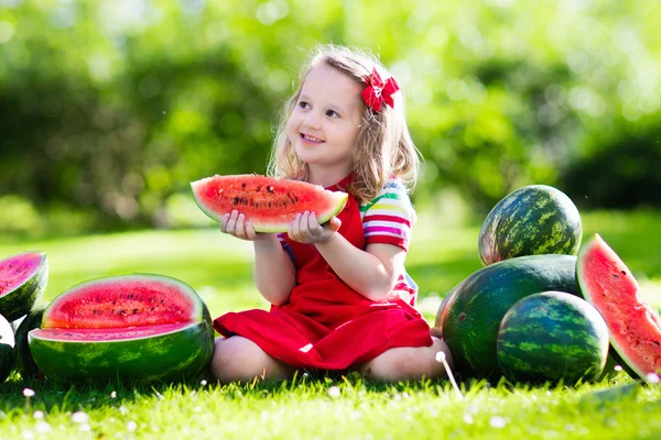 Little girl eating watermelon in the garden