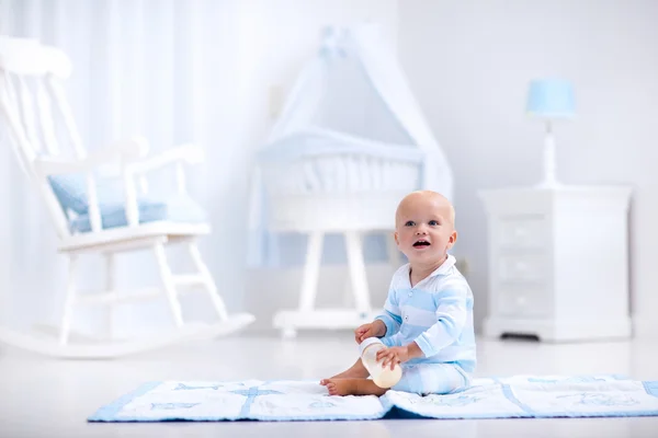 Baby boy drinking milk in sunny nursery