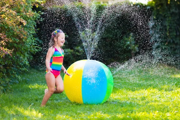 Little girl playing with toy ball garden sprinkler