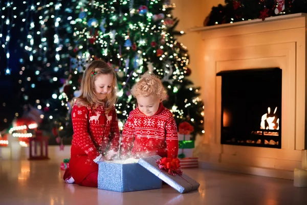 Kids opening Christmas presents at fireplace