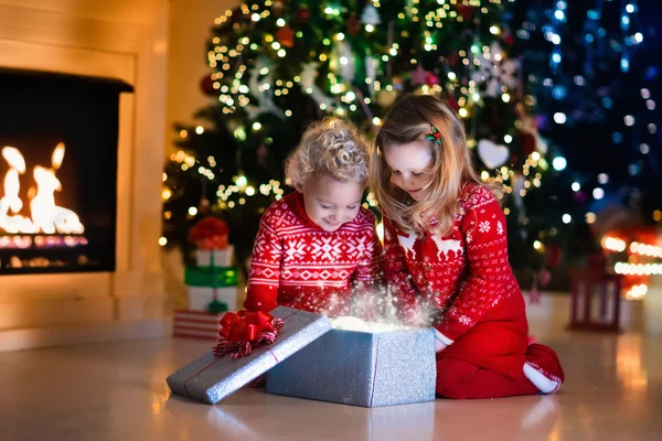 Kids opening Christmas presents at fireplace