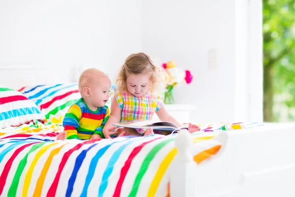 Two children reading a book in bed