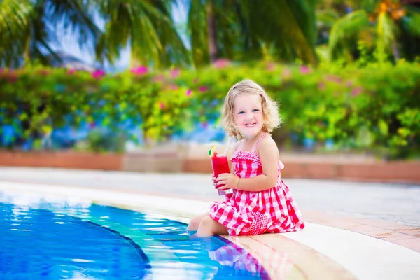 Little girl drinking juice at a swimming pool