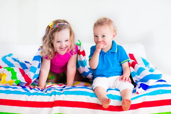 Children sleeping under colorful blanket