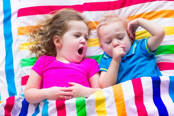 Children sleeping under colorful blanket