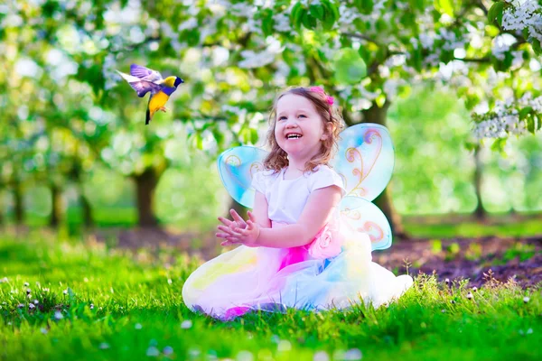 Little girl in fairy costume feeding a bird