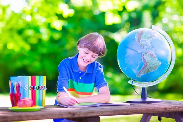 School boy doing homework in school yard