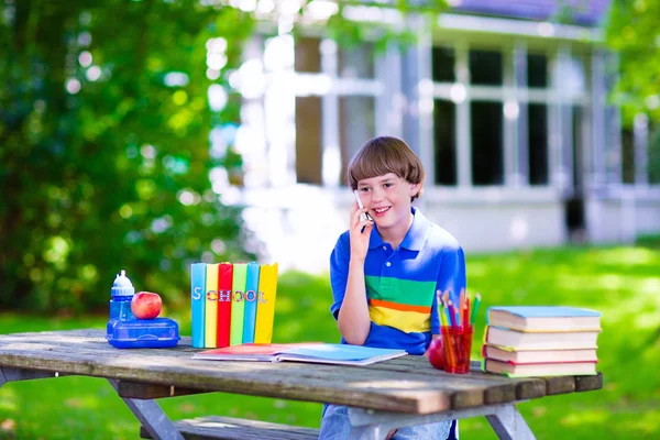 Child in school yard studying and talking on the phone