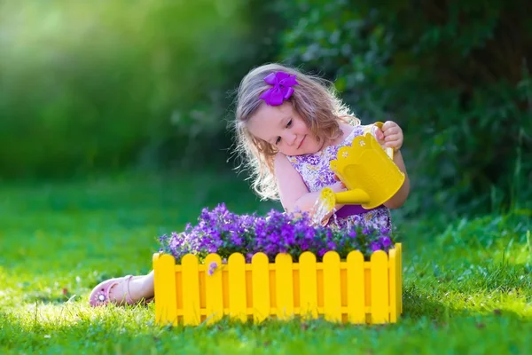 Little girl working in the garden watering flowers