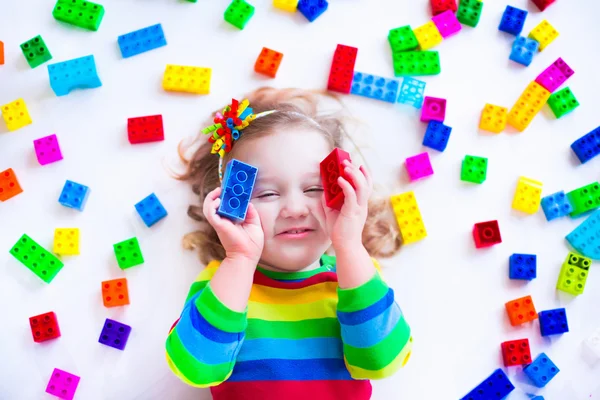 Little girl playing with colorful toy blocks