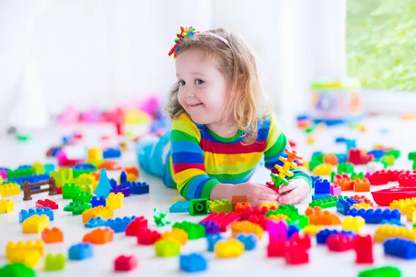 Little girl playing with colorful toy blocks