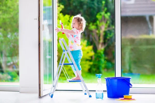 Little girl washing a window