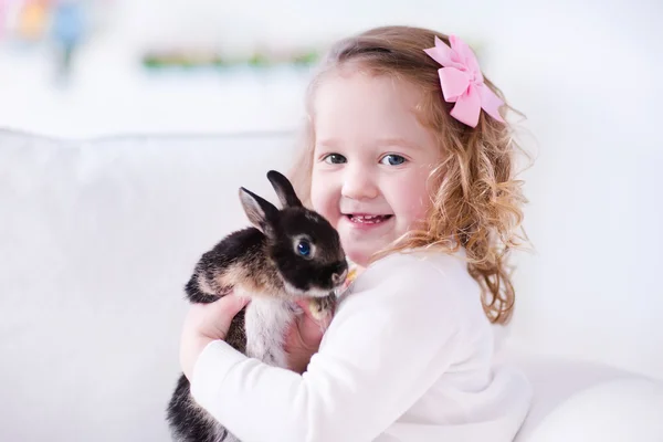 Little girl playing with a real pet rabbit