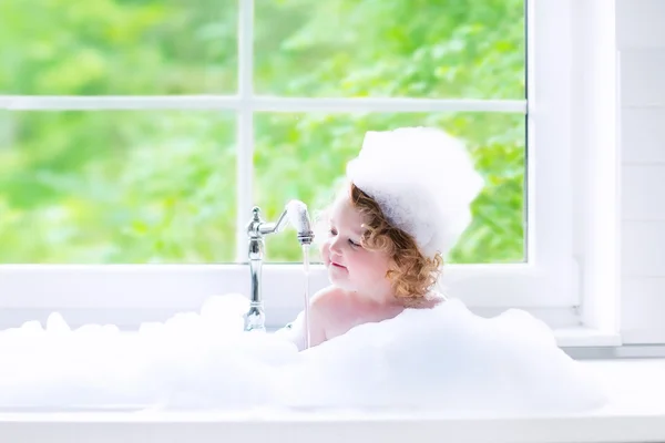 Baby girl taking bath with foam