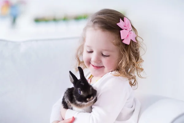 Little girl playing with a real pet rabbit