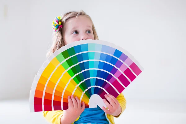 Little girl choosing paint color for wall