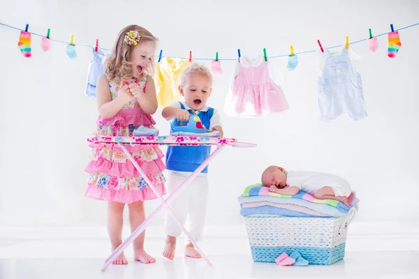 Kids ironing clothes for baby brother