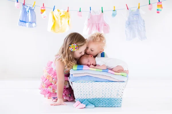 Brother and sister kissing newborn baby