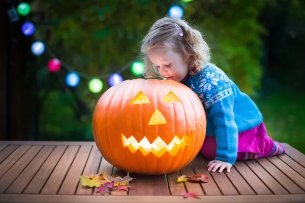 Little girl carving pumpkin at Halloween