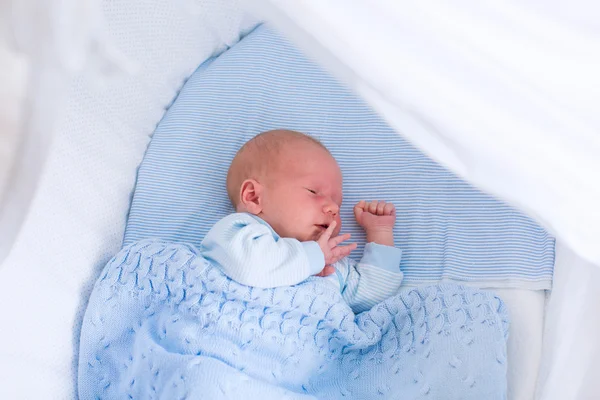 Newborn baby boy in white bassinet