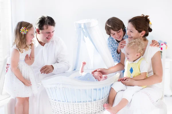 Family playing with newborn child in white bassinet