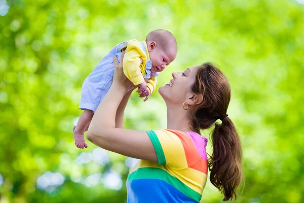 Mother holding newborn baby in a park