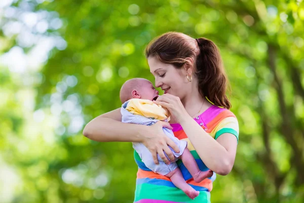 Mother holding newborn baby in a park