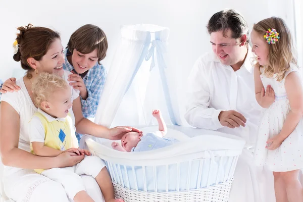 Happy family watching new baby in a white crib