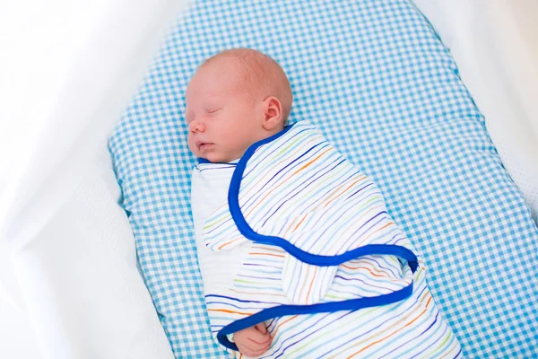 Little swaddled baby in white bed