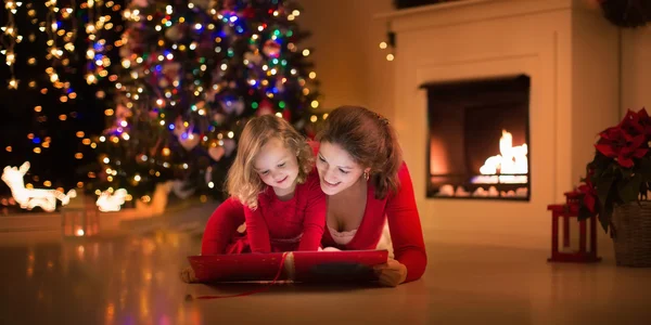 Mother and daughter reading at fire place on Christmas eve
