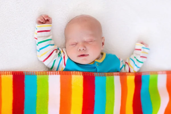 Little baby boy sleeping under colorful blanket