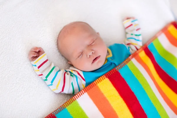 Little baby boy sleeping under colorful blanket