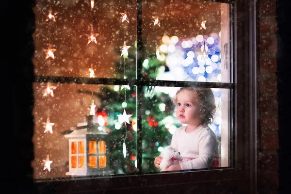 Little girl sitting at a window on Christmas eve