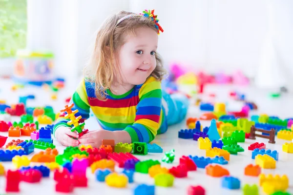 Little girl playing with colorful toy blocks