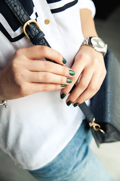 Modern girl with green nail Polish and a trendy bag in stylish jeans. The style life, trending