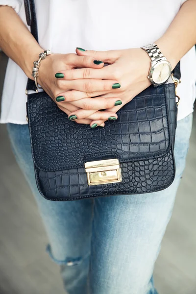 Modern girl with green nail Polish and a trendy bag in stylish j