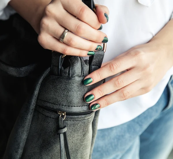 Modern girl with green nail Polish and a trendy bag in stylish jeans. The style life, trending
