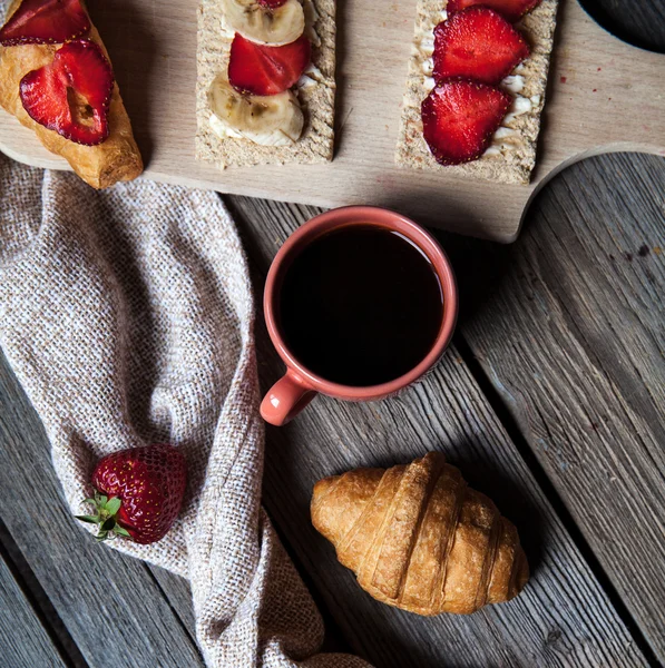 Delicious breakfast with a cup of coffee and fruit sandwiches, croissants. Strawberries, food, drink, chocolate.