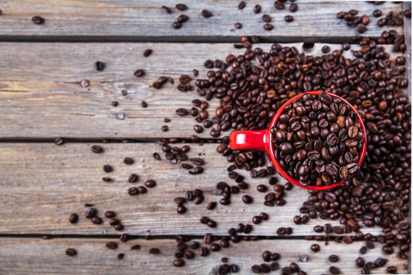 Coffee beans and red coffee cup on wooden background. Drink